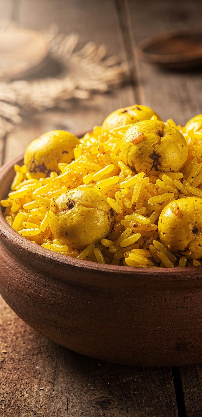 Tigela de barro com arroz amarelo e frutos de pequi inteiros