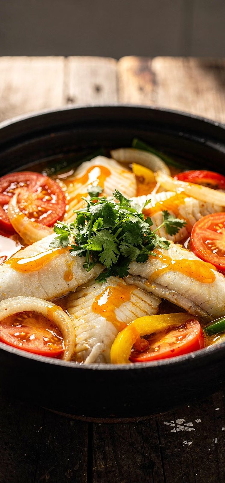 Panela de barro com postas de peixe branco, tomate, cebola, pimentão e coentro